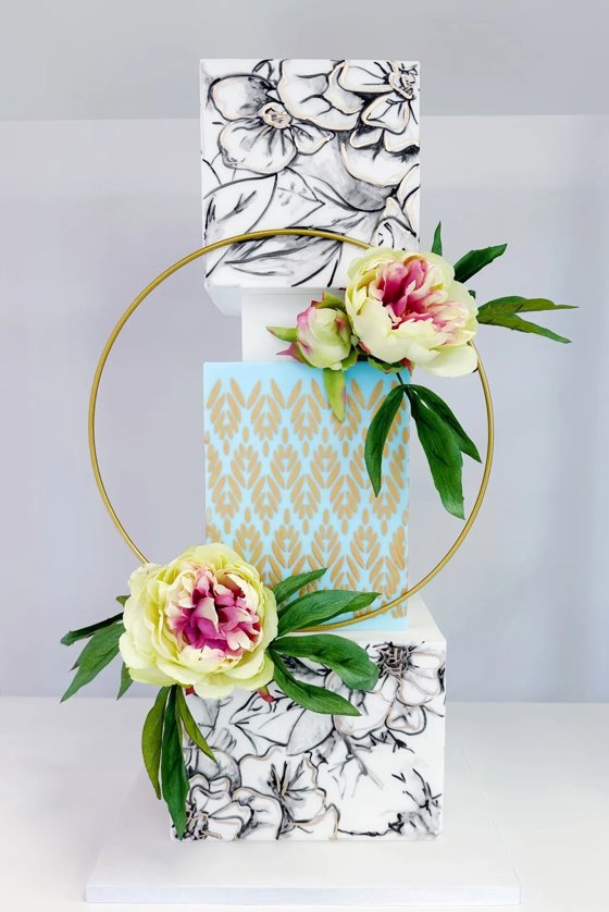  Colourful, contemporary tiered cake with different patterns with golden circle decorated with flowers